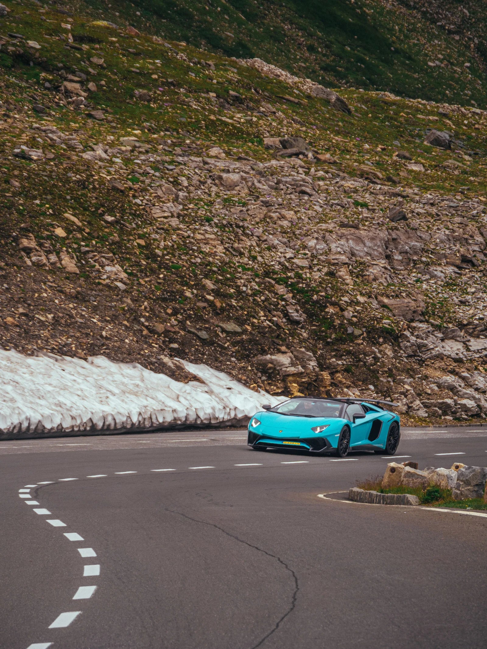 A modern blue sports car on a winding mountain road.