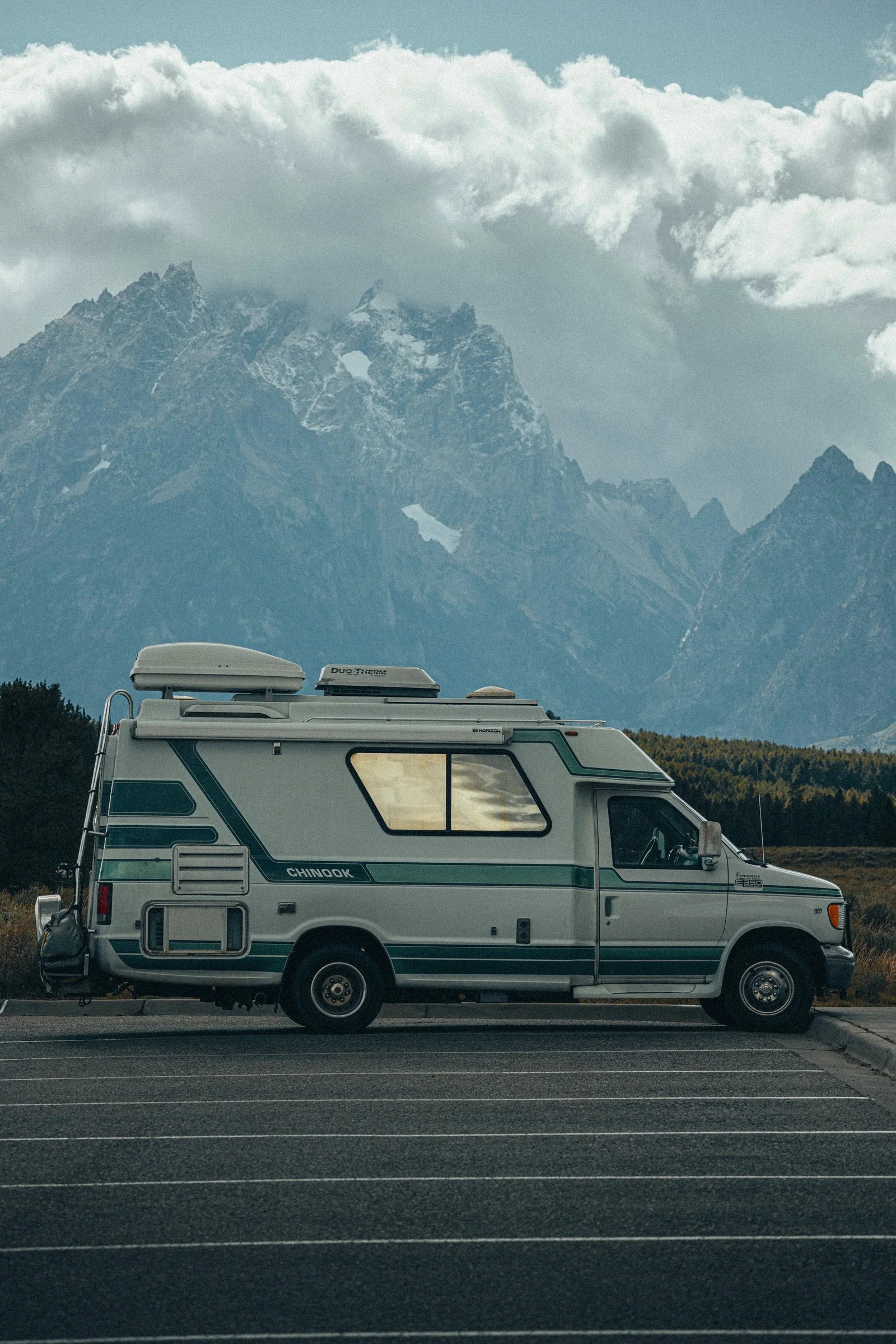 A recreational vehicle beneath a dramatic mountain landscape.