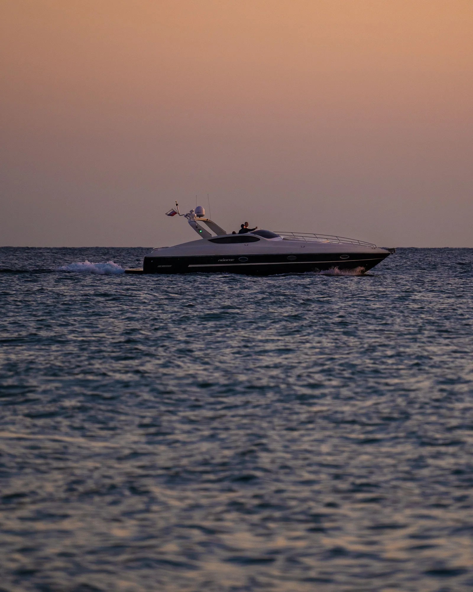 An elegant motorboat on calm water at sunset.