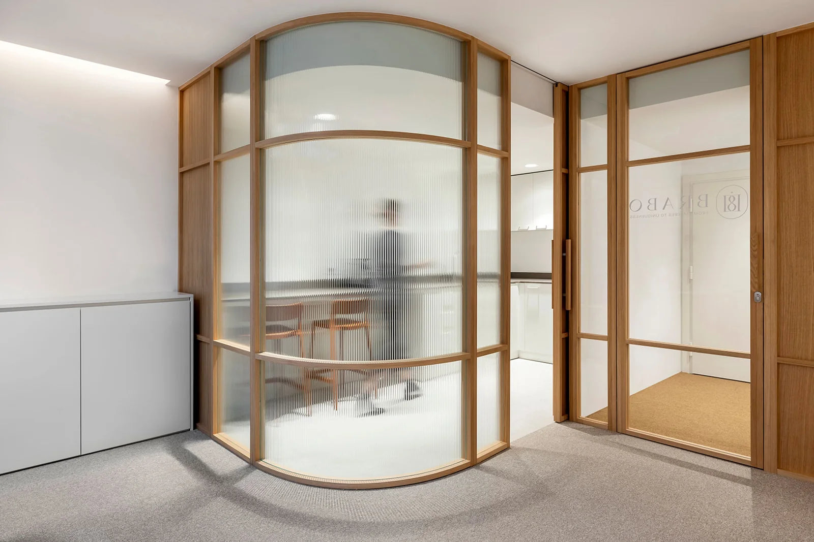 A contemporary office with curved glass partitions and warm wood details.